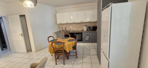 a kitchen with a table and chairs and a refrigerator at T3 spacieux lumineux jardin et proche du tram in Pont-de-la-Maye