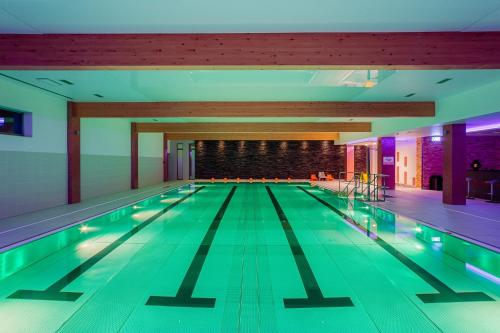 a swimming pool in a building with green lanes at Hotel TENIS in Zvolen