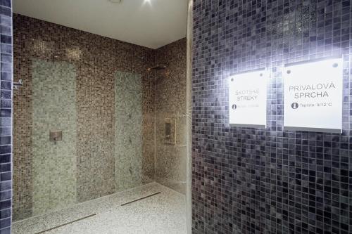 a bathroom with a shower with blue tiled walls at Hotel TENIS in Zvolen