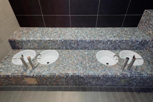 a counter with three sinks in a bathroom at Hotel TENIS in Zvolen