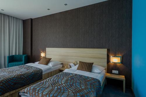 a hotel room with two beds and a chair at Hotel TENIS in Zvolen
