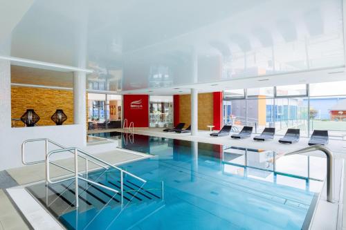 a swimming pool with chairs in a building at Hotel TENIS in Zvolen