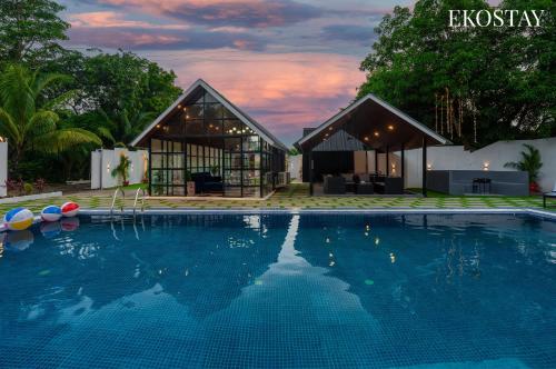 a house with a swimming pool in front of a building at EKOSTAY - Oakwood Chalet in Alibaug