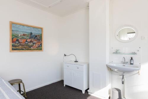 a white bathroom with a sink and a mirror at Welcome in - Vakantiewoning in het centrum met tuin en airco, Zoutelande in Zoutelande