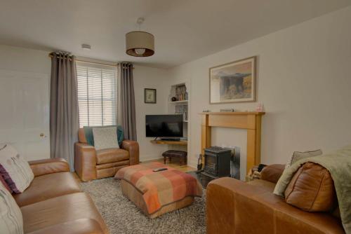 a living room with leather furniture and a fireplace at Wilsons, Golspie in Golspie