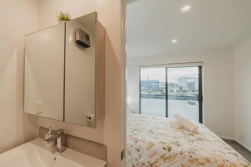 a bathroom with a bed and a sink and a window at Downtown Bliss - 4-BR Retreat Amidst the Cityscape in Christchurch