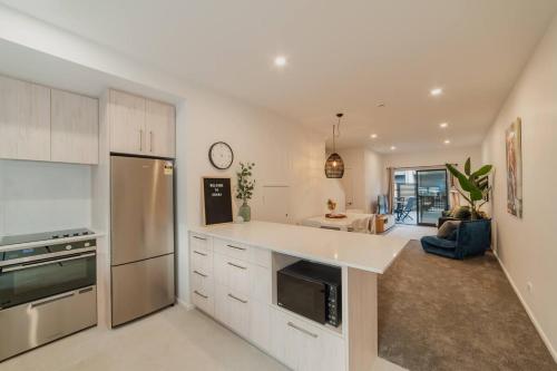 a kitchen with a white counter top and a living room at Downtown Bliss - 4-BR Retreat Amidst the Cityscape in Christchurch