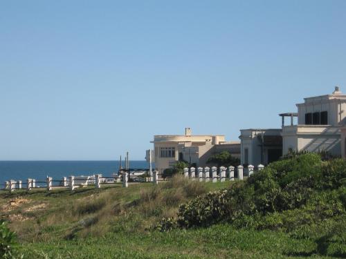 a white fence on a hill next to the ocean at Posada Cova Del Sol in La Pedrera