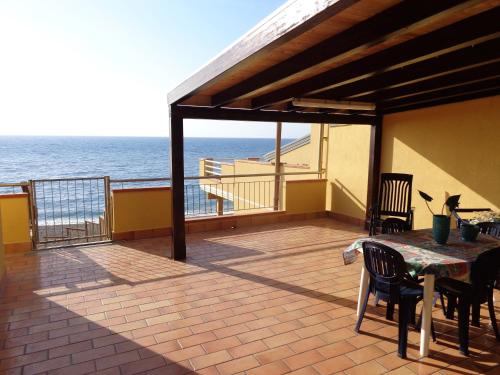 Un balcón con mesa y sillas y el mar. en Casa con terrazzo e scala diretta sul mare, en Capo dʼOrlando