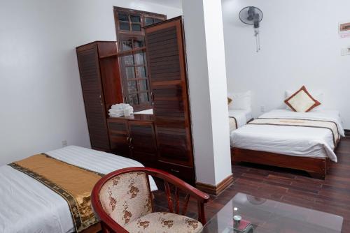 a room with two beds and a chair and a mirror at Khách Sạn Như Mai in Quang Tri