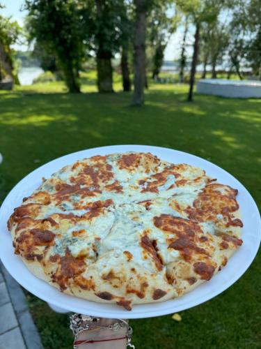 a person holding a pizza on a white plate at Potcoava Dunarii in Suhaia