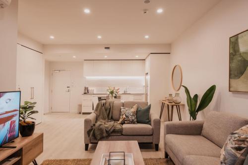a living room with two couches and a tv at Serene Spaces on Tuam - 2 Bedroom Apartment in Christchurch