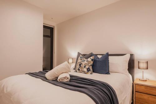 a bedroom with a large bed with blue pillows at Serene Spaces on Tuam - 2 Bedroom Apartment in Christchurch