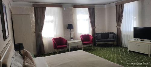 a hotel room with two chairs and a bed and a television at BEK PLUS HOTEL in Takchilik