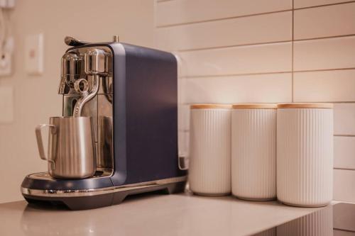 a juicer sitting on a counter next to three rolls of paper towels at Serene Spaces on Tuam - 2 Bedroom Apartment in Christchurch