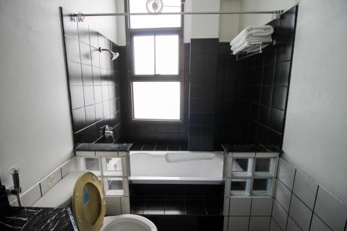 a bathroom with a tub and a toilet and a window at Sourire at Rattanakosin Island Hotel in Bangkok