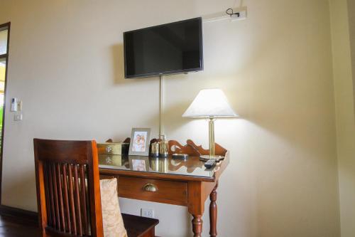 a desk with a lamp and a television on a wall at Sourire at Rattanakosin Island Hotel in Bangkok