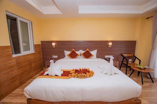 a bedroom with a large white bed with a wooden headboard at Hotel Hidden Kingdom in Pokhara