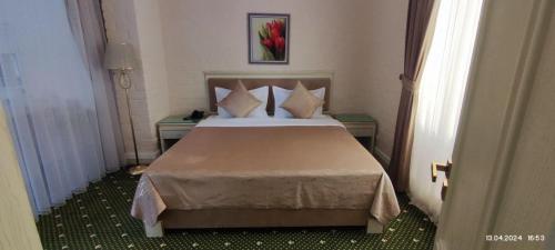 a bedroom with a bed with pillows and two tables at BEK PLUS HOTEL in Takchilik