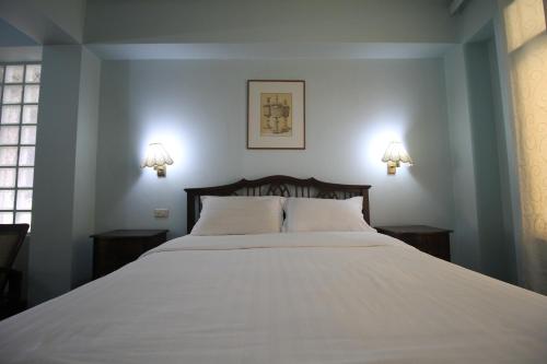 a bedroom with a large white bed with two lamps at Sourire at Rattanakosin Island Hotel in Bangkok
