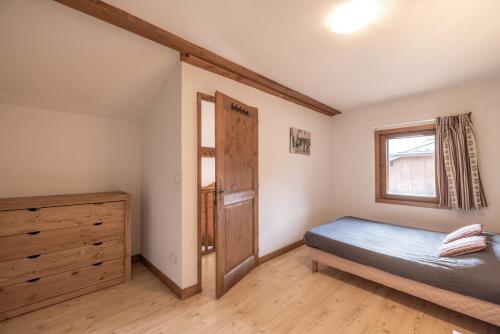 ein Schlafzimmer mit einem Bett, einer Kommode und einem Fenster in der Unterkunft Les Fermes de Samoëns in Samoëns