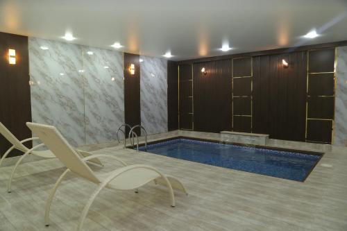 a pool in a room with two chairs and a table at BEK PLUS HOTEL in Takchilik