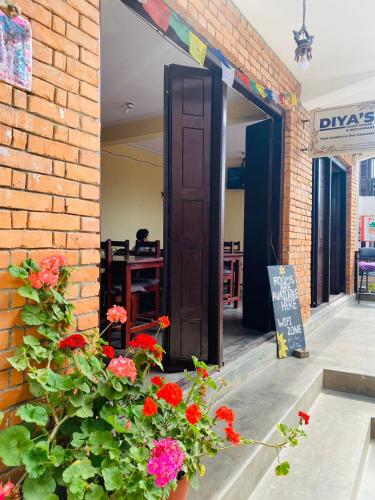 an open door to a brick building with flowers at Diya's Guest House - Family Environment in Bandīpur