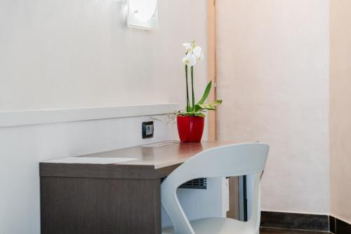 a white chair sitting next to a desk with a flower on it at Hotel Milano Navigli in Milan