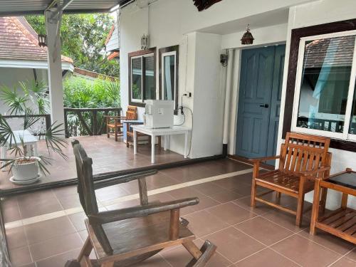 a porch with a rocking chair and a blue door at Villas Chalitaa วิลล่าชาลิตา in Chiang Mai