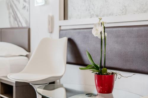 a red vase with a white flower on a table at Hotel Milano Navigli in Milan