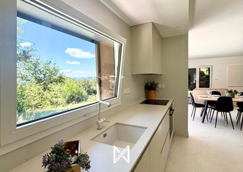 a kitchen with a sink and a large window at MyStay - Encosta da Barragem in Fafe
