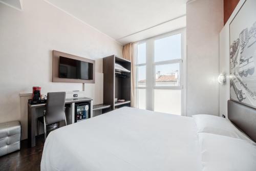 a hotel room with a white bed and a desk at Hotel Milano Navigli in Milan
