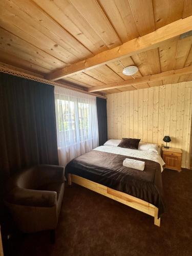 a bedroom with a bed and a chair in it at Willa Pod Orłem Jacuzzi Sauna in Kościelisko