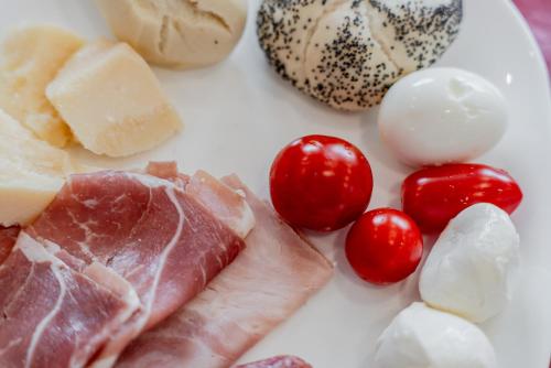 a plate of food with meat tomatoes and cheese at Hotel Milano Navigli in Milan