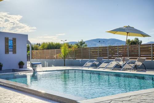 a swimming pool with chairs and an umbrella at Tommy's Rooms in Haraki
