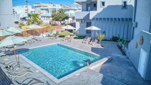 a swimming pool with chairs and umbrellas next to a building at Tommy's Rooms in Haraki