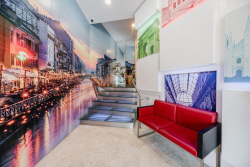 a red bench in a room with a mural of a city at Hotel Milano Navigli in Milan