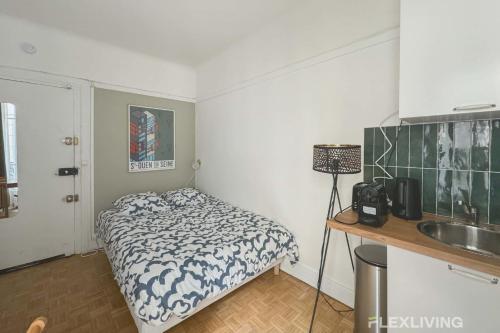 une petite chambre avec un lit et un lavabo dans l'établissement Flexliving - Studio - Championnet, à Paris