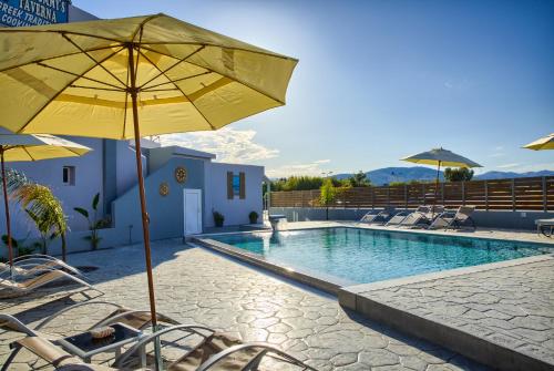 a swimming pool with chairs and a yellow umbrella at Tommy's Rooms in Haraki