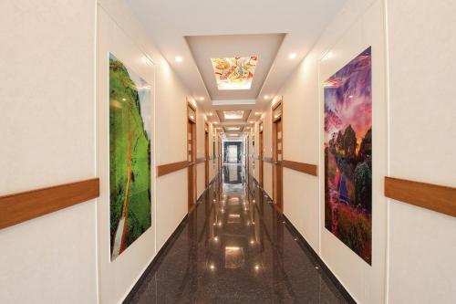 a corridor in a building with paintings on the walls at FabHotel Prime Suloka Towers - 500m from View point, Kaveri River in Kushālnagar