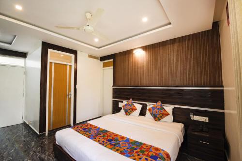 a bedroom with two beds and a wooden headboard at FabHotel Prime Suloka Towers - 500m from View point, Kaveri River in Kushālnagar