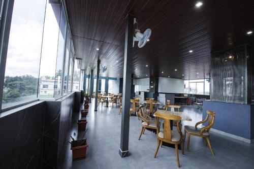 a restaurant with wooden tables and chairs and windows at FabHotel Prime Suloka Towers - 500m from View point, Kaveri River in Kushālnagar