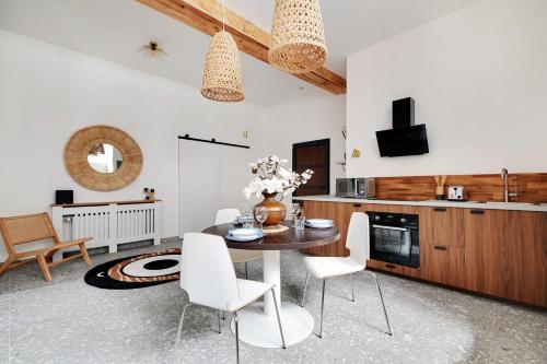 - une cuisine avec une table et des chaises blanches dans la chambre dans l'établissement Authentique Apartment - 1BR-4P - Saint-Ouen, à Saint-Ouen