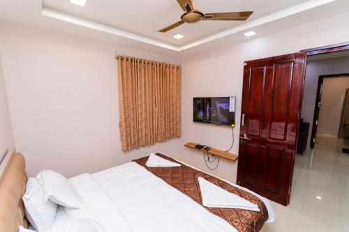 a bedroom with a bed and a flat screen tv at Magan Enclave in Kuttālam