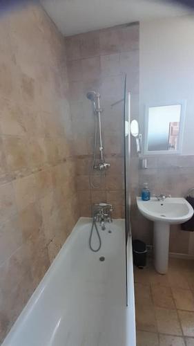a bathroom with a bath tub and a sink at Well Cottage in Beckington