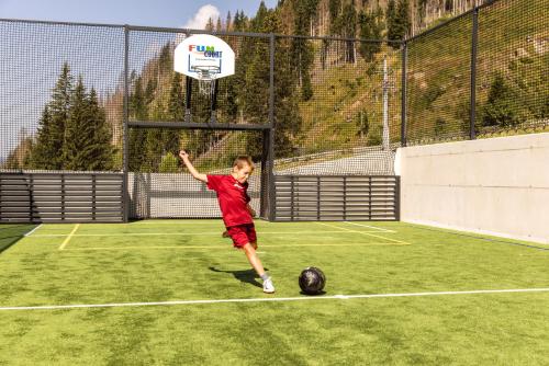 a young boy throwing a frisbee at a basketball hoop at Almfamilyhotel Scherer in Obertilliach