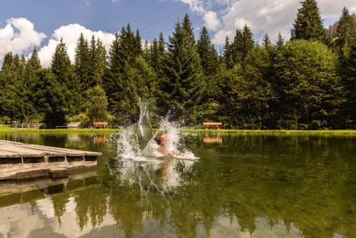 a person swimming in a pond with a fountain at Almfamilyhotel Scherer in Obertilliach