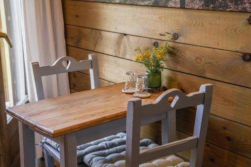 a wooden table with two chairs and a vase with flowers at Minds & Mountains Eco Lodge in La Molina