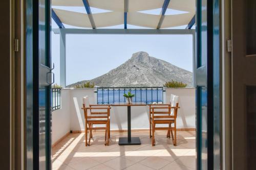 a table and chairs on a balcony with a view of a mountain at Elena Village Hotel & Suites in Kalymnos