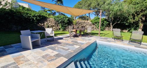 a patio with a table and chairs next to a pool at St-Clair Villa, piscine & pinède in Sète